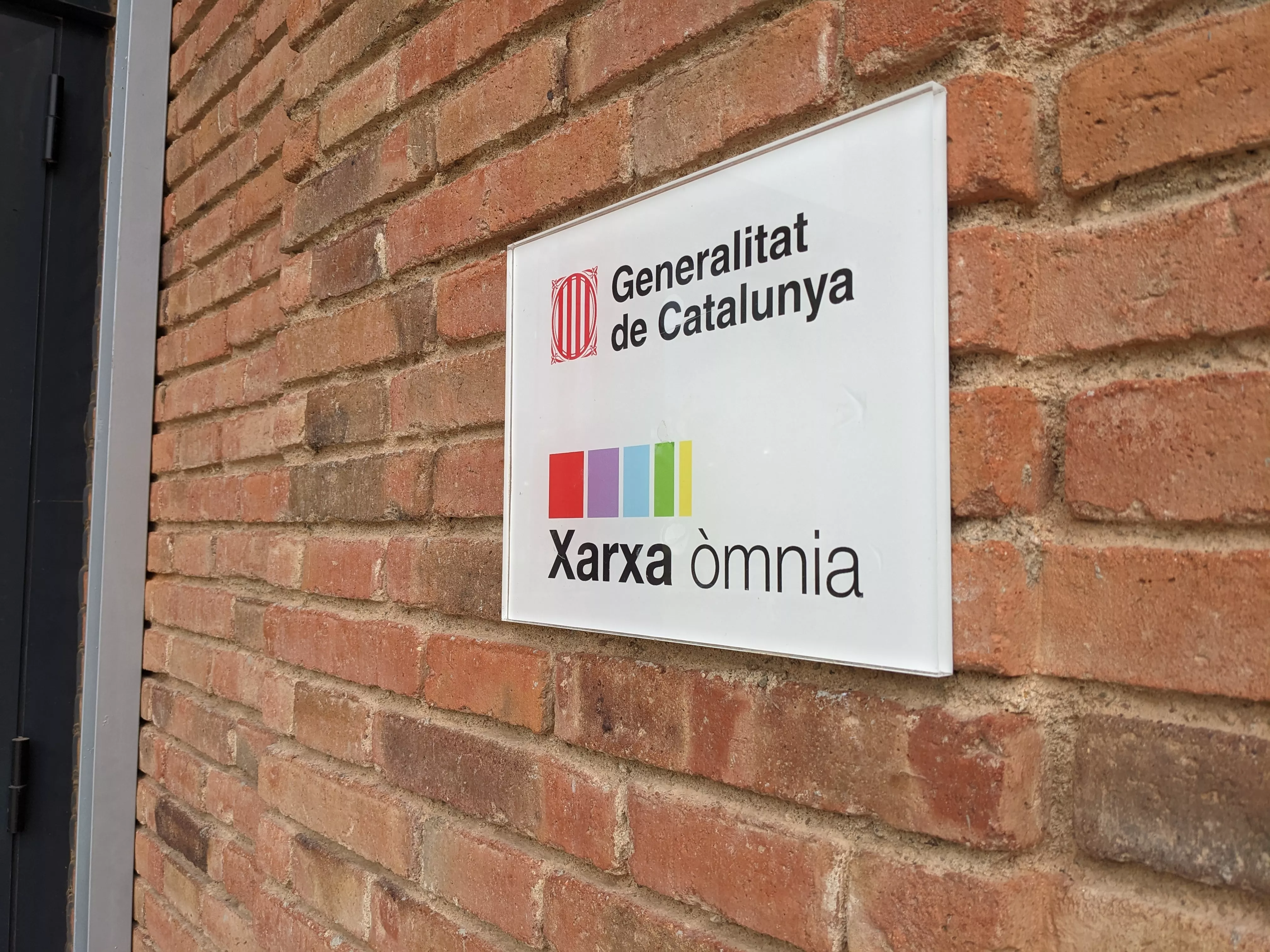 Placa identificativa del Punt Òmnia a l'entrada de les Escoles Velles