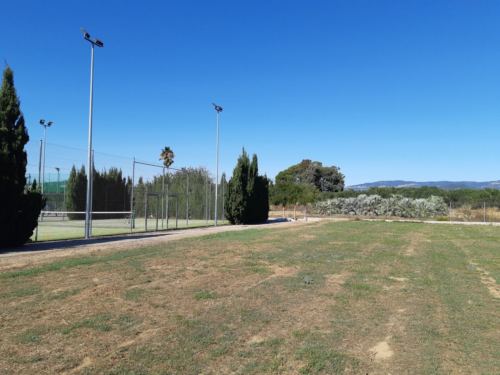 La pista de tennis actual, a l'esquerra de la imatge, i terrenys on es construïa la nova pista prevista en el pressupost La pista de tennis actual, a l'esquerra de la imatge, i terrenys on es construïa la nova pista prevista en el pressupost